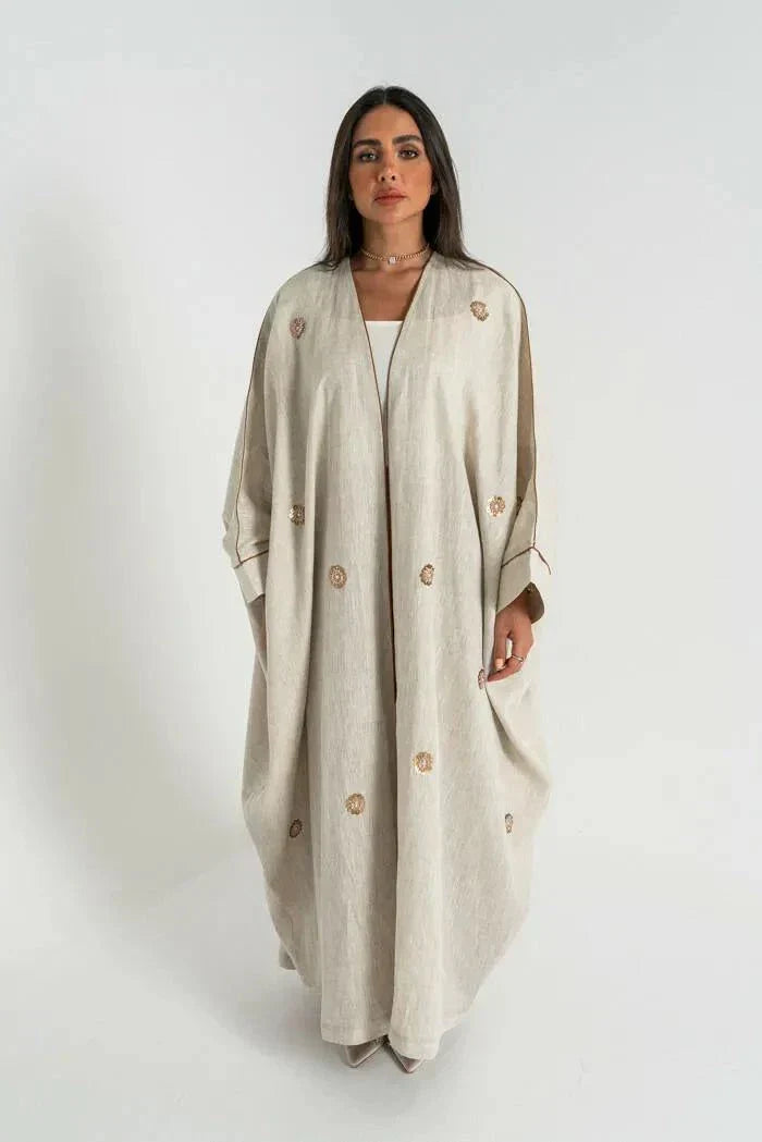 woman wearing beige linen bisht abaya with delicate hand embroidery and relaxed fit