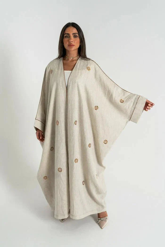 woman wearing beige linen bisht abaya with delicate hand embroidery and relaxed fit