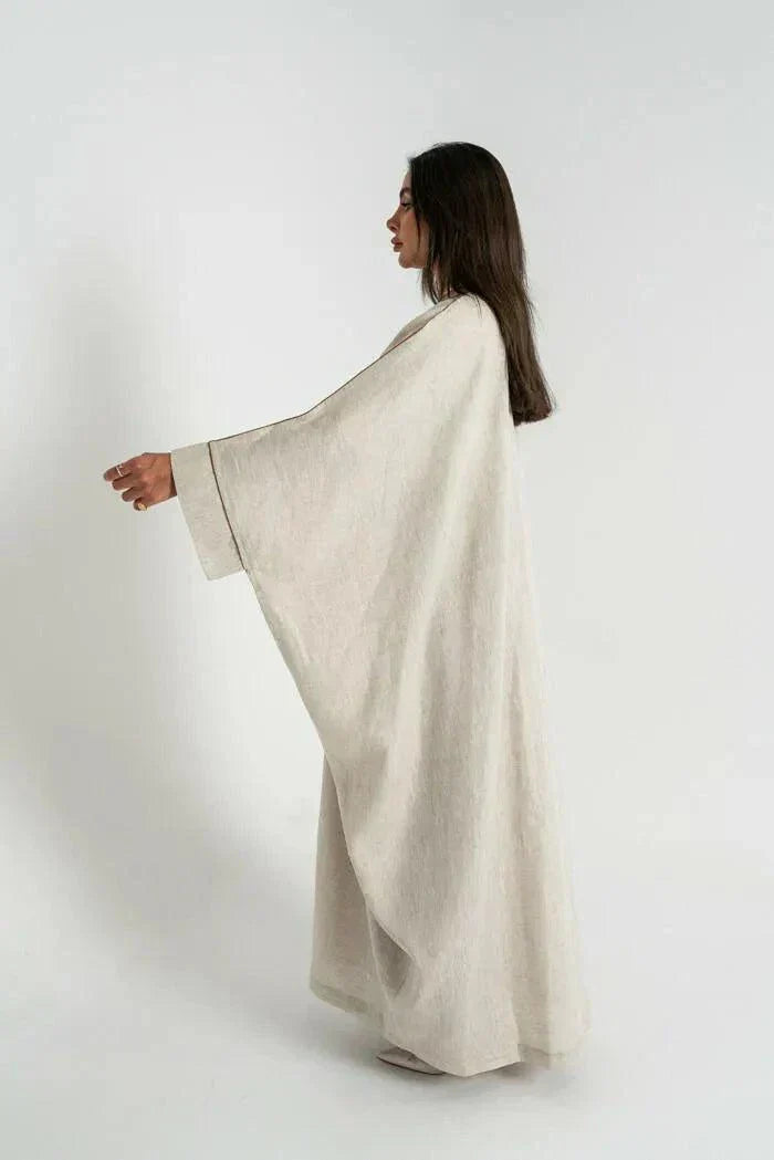 woman wearing beige linen bisht abaya with delicate hand embroidery and relaxed fit