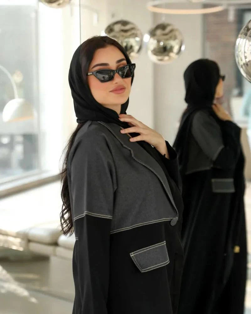 Woman wearing Ashden black abaya with gray washed-jean two-tone panel, contrast stitching, and flap pocket in modern urban style