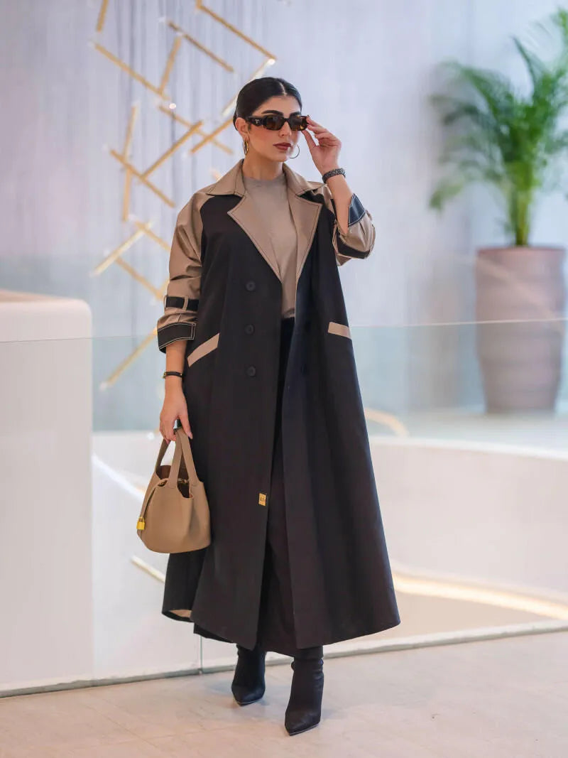 woman wearing a two-tone long structured blazer in black and olive-beige with sunglasses and a beige handbag