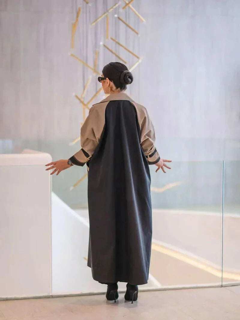 woman wearing long structured two-tone black and olive beige blazer abaya with double-breasted front and contrast sleeves carrying beige handbag - long structured blazer