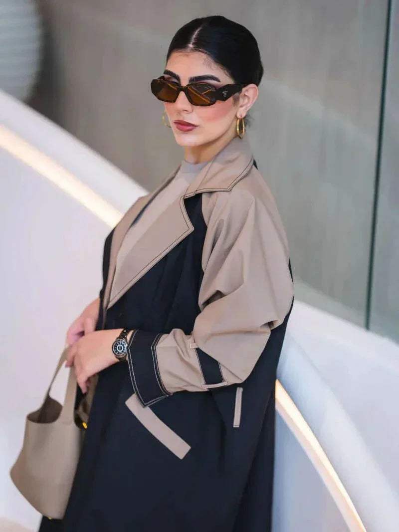 woman wearing long structured two-tone black and olive beige blazer abaya with double-breasted front and contrast sleeves carrying beige handbag - long structured blazer