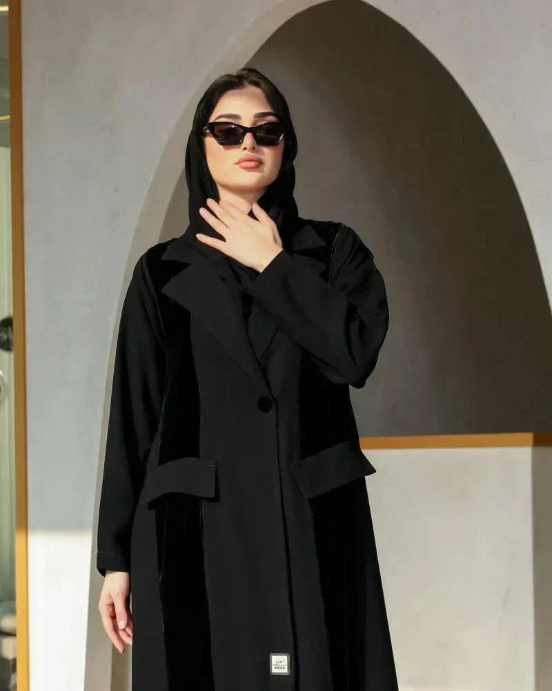 Woman wearing a black blazer-style abaya with structured lapels and single-button closure in a flowy crepe fabric.
