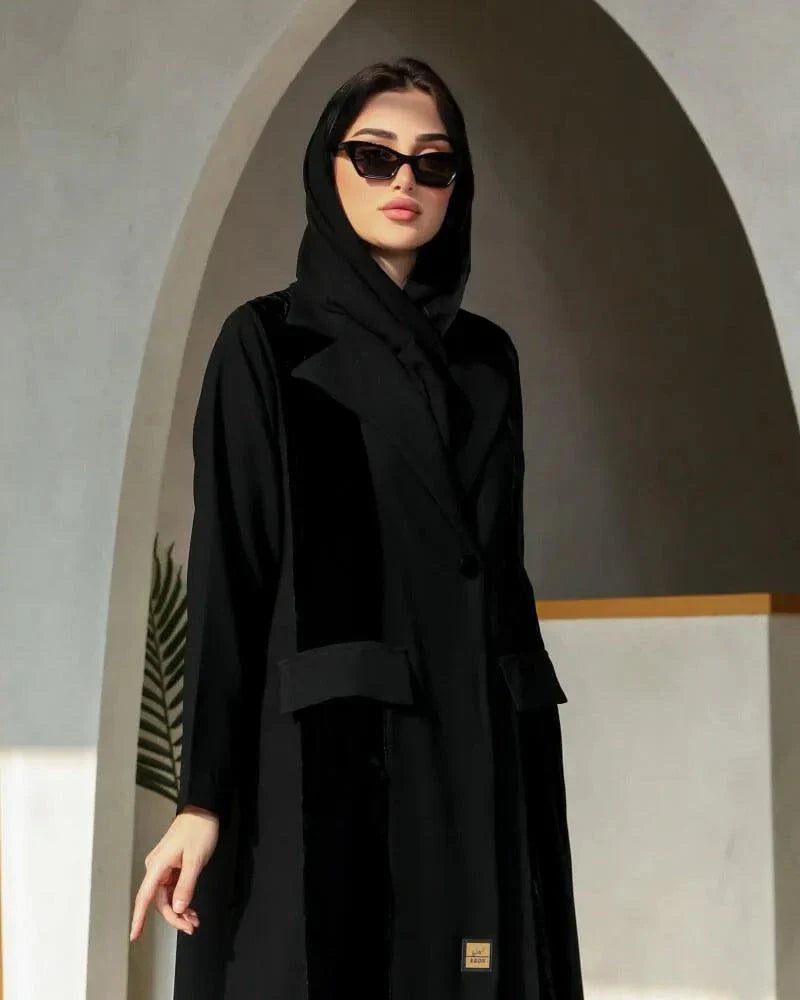 Woman wearing a black blazer-style abaya with structured lapels and single-button closure in a flowy crepe fabric.