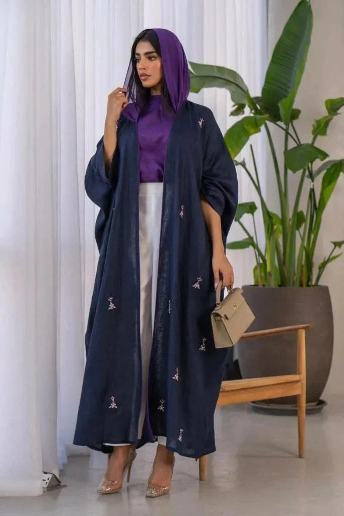 Woman wearing a navy blue Mystic bisht with subtle purple lines and hand-stitched accents paired with a purple blouse and white pants.
