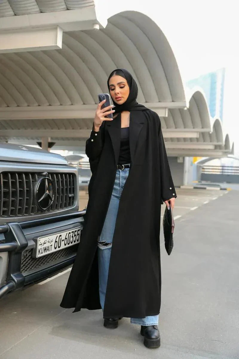 woman wearing classic black abaya with soft crepe fabric draped elegantly outdoors near car