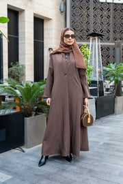 woman wearing classic brown crepe abaya with hijab and sunglasses outdoors carrying a small handbag