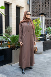 Woman wearing classic brown crepe abaya with hijab and sunglasses outdoors