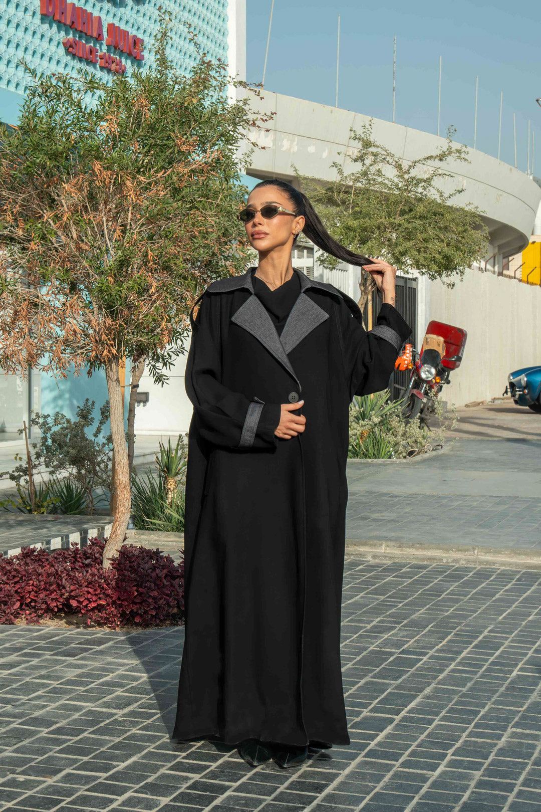 Woman wearing black crepe abaya with grey lapels and cuffs in urban outdoor setting