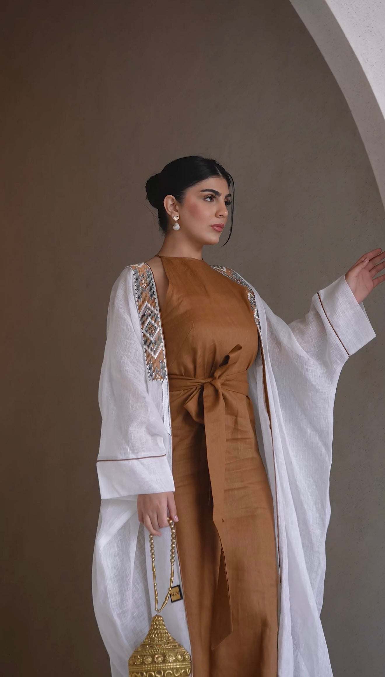 white bisht with tribal embroidery and brown piping over brown dress