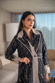 woman wearing elegant black and beige patterned Ashira abaya holding tan handbag in modern living room