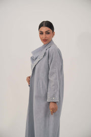 Woman wearing a soft blueish gray lightweight blazer-style abaya with wide open lapel and embellished pearl and crystal cuffs