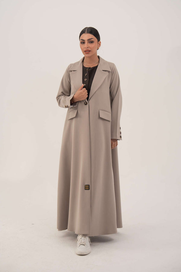 woman wearing light taupe beige blazer with notched collar and single front button standing against white background