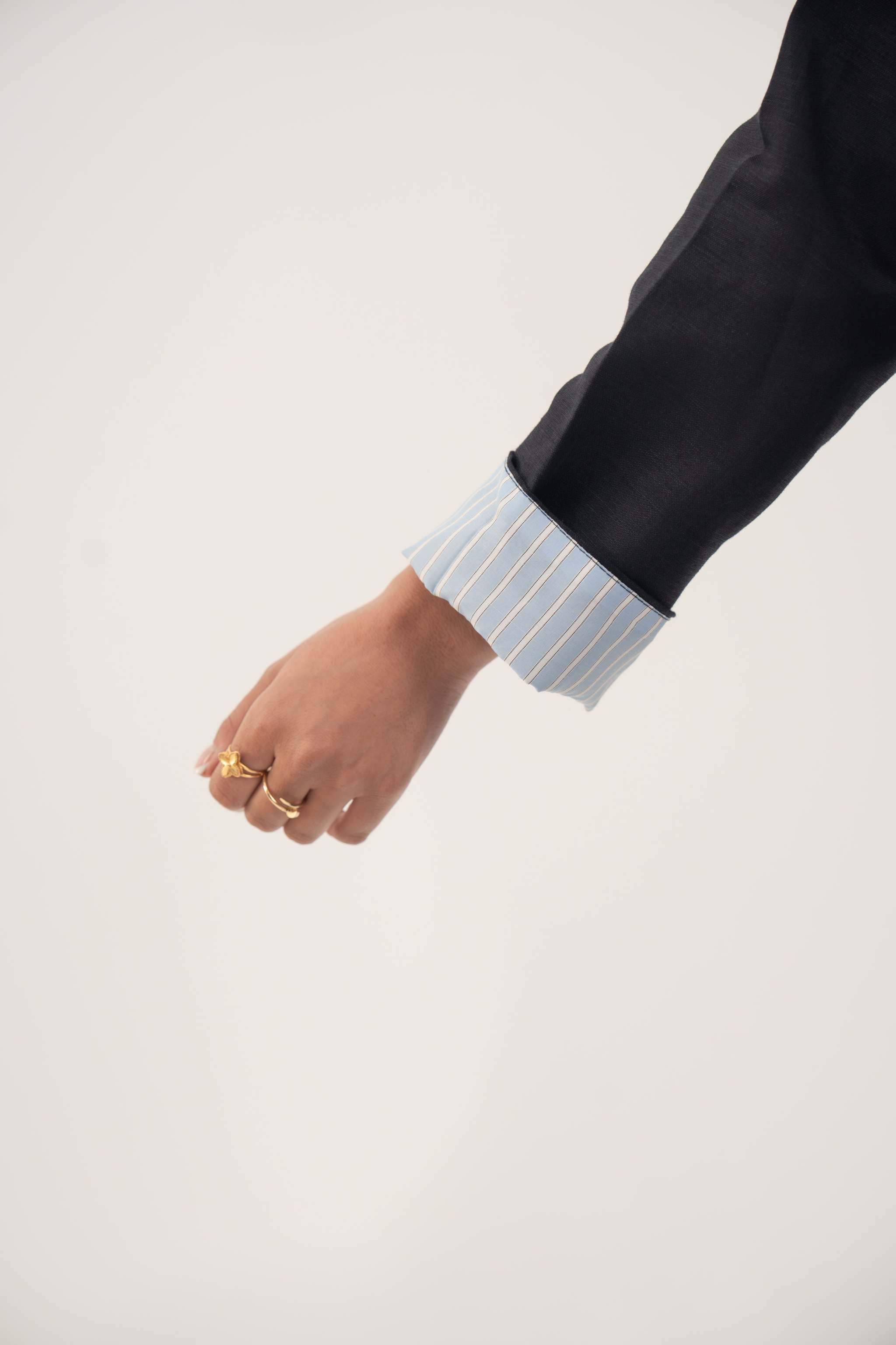 Close-up of azura abaya sleeve with folded blue and white pinstripe cuff on soft navy linen blend fabric