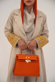 Beige linen abaya with tailored blazer cut and vibrant orange, gold, green embroidery on sleeves, paired with orange headscarf and handbag - sophisticated abaya