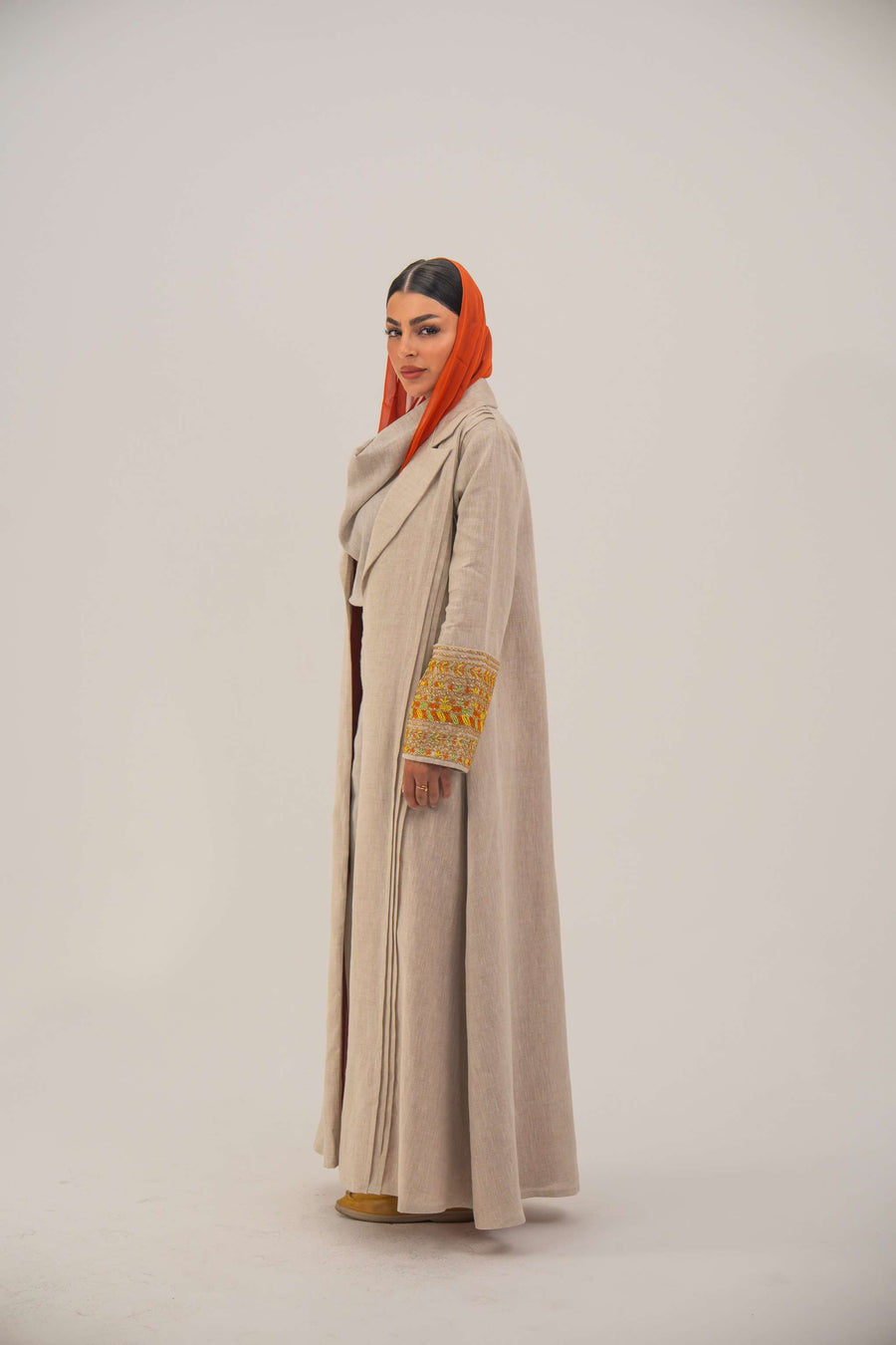 Beige linen blend abaya with tailored blazer-style cut, vibrant orange, gold, and green embroidery on sleeves, and orange chiffon lining detail - sophisticated abaya