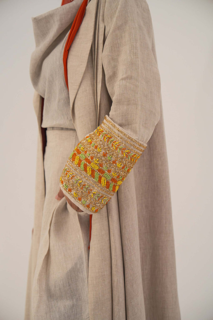 Beige linen abaya with orange, gold, and green shak embroidery on wide lapels and sleeves, featuring a vibrant orange chiffon lining - sophisticated abaya