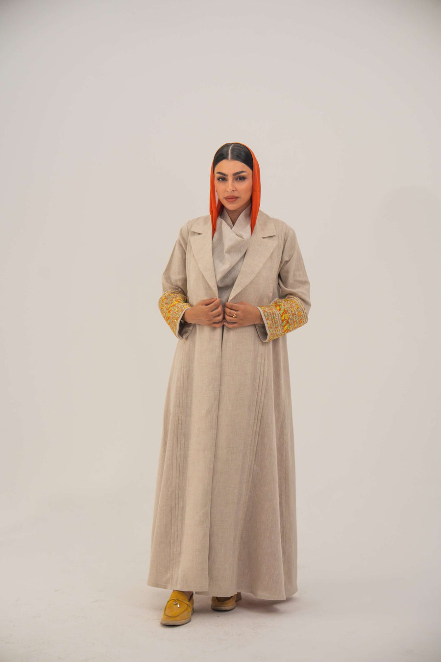 Beige linen blend abaya with blazer-style cut and vibrant orange, gold, and green shak embroidery on sleeves, featuring orange chiffon lining - sophisticated abaya