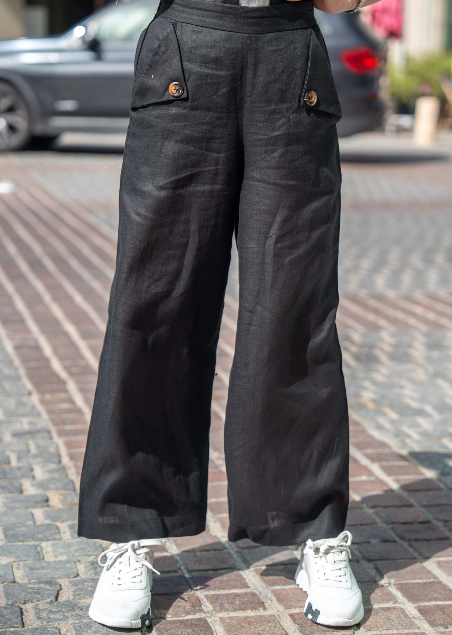 black wide-leg Mist Pant with front buttoned pockets and white sneakers on cobblestone street