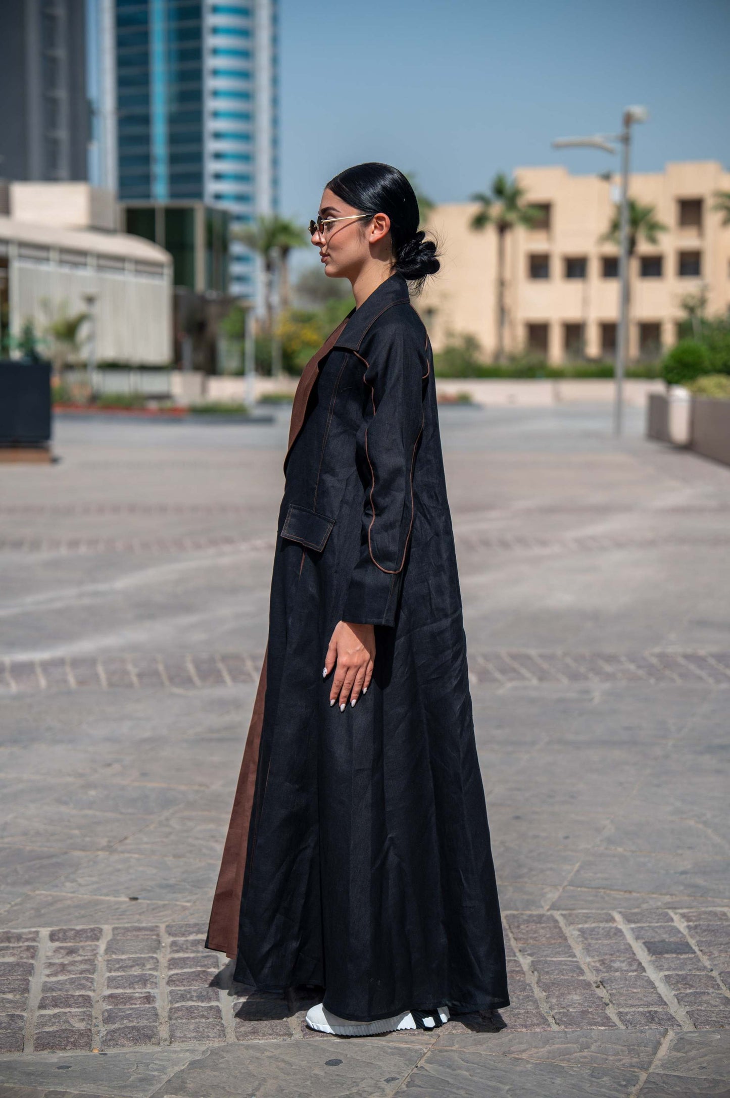 model wearing Velora black and brown linen abaya with wide lapels and structured street-style cut outdoors