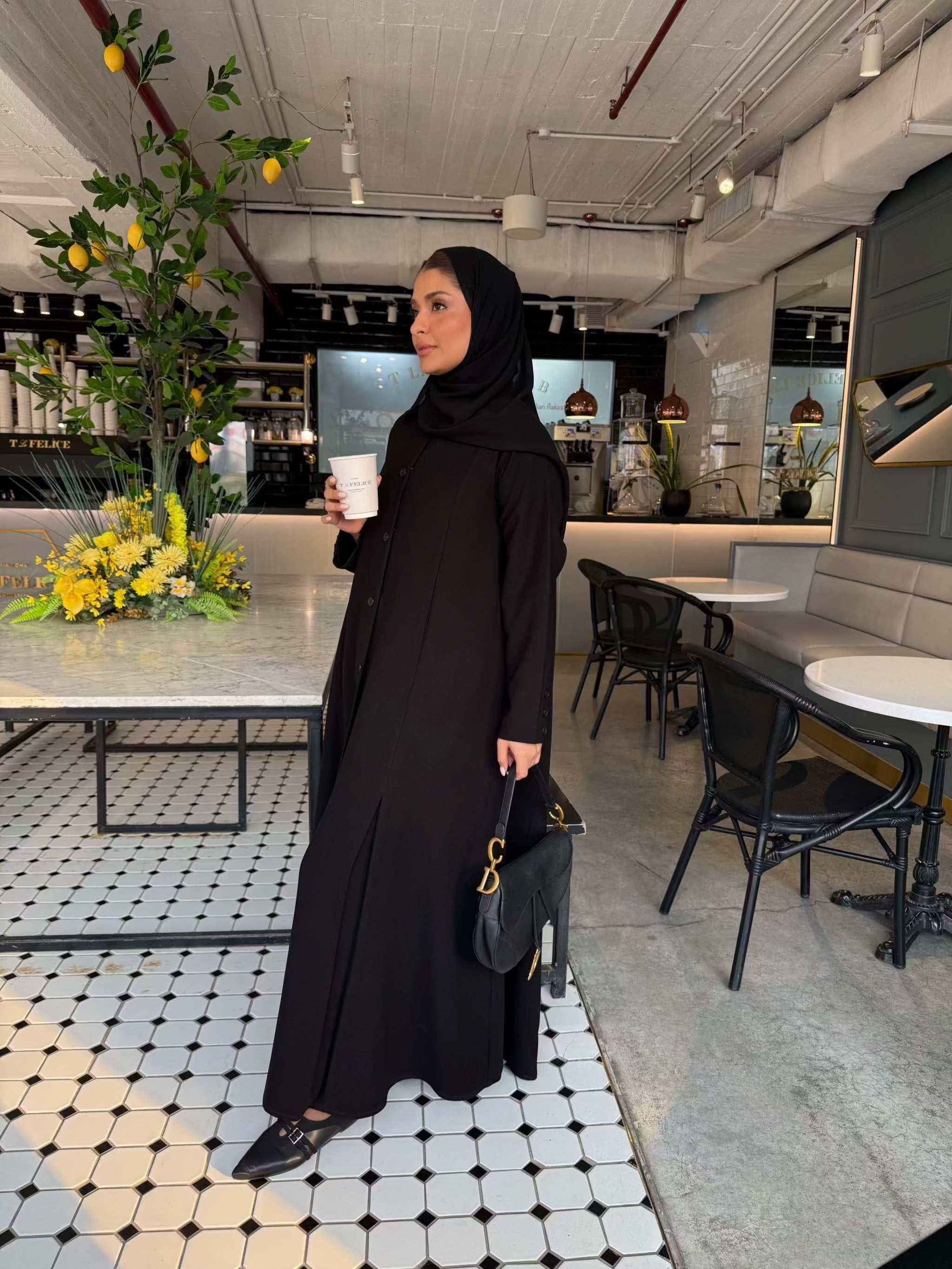 Elegant black crepe abaya with button-down front and subtle pleated skirt detail, worn with a black hijab - The Sophisticated Crepe Abaya