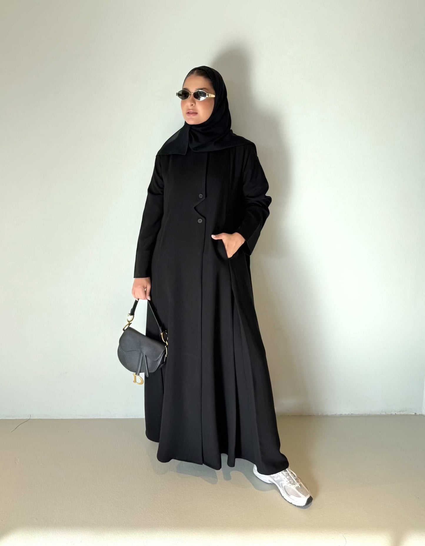 Black flowing crepe abaya with full button-down front, lightweight and elegant, styled with a black hijab and sunglasses.