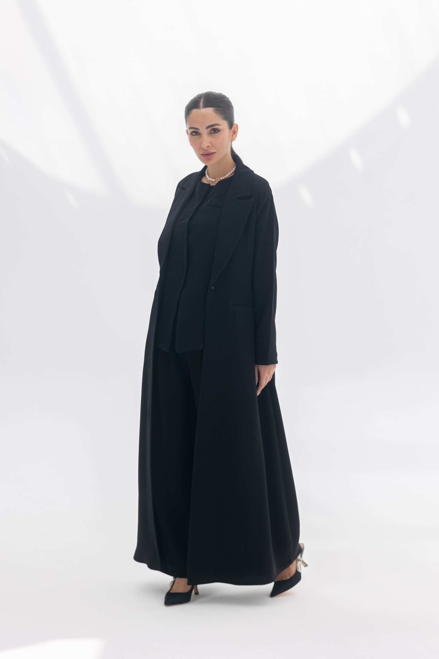 Woman wearing a tailored black crepe blazer abaya with matching wide-leg pants and black inner, styled elegantly for formal occasions.