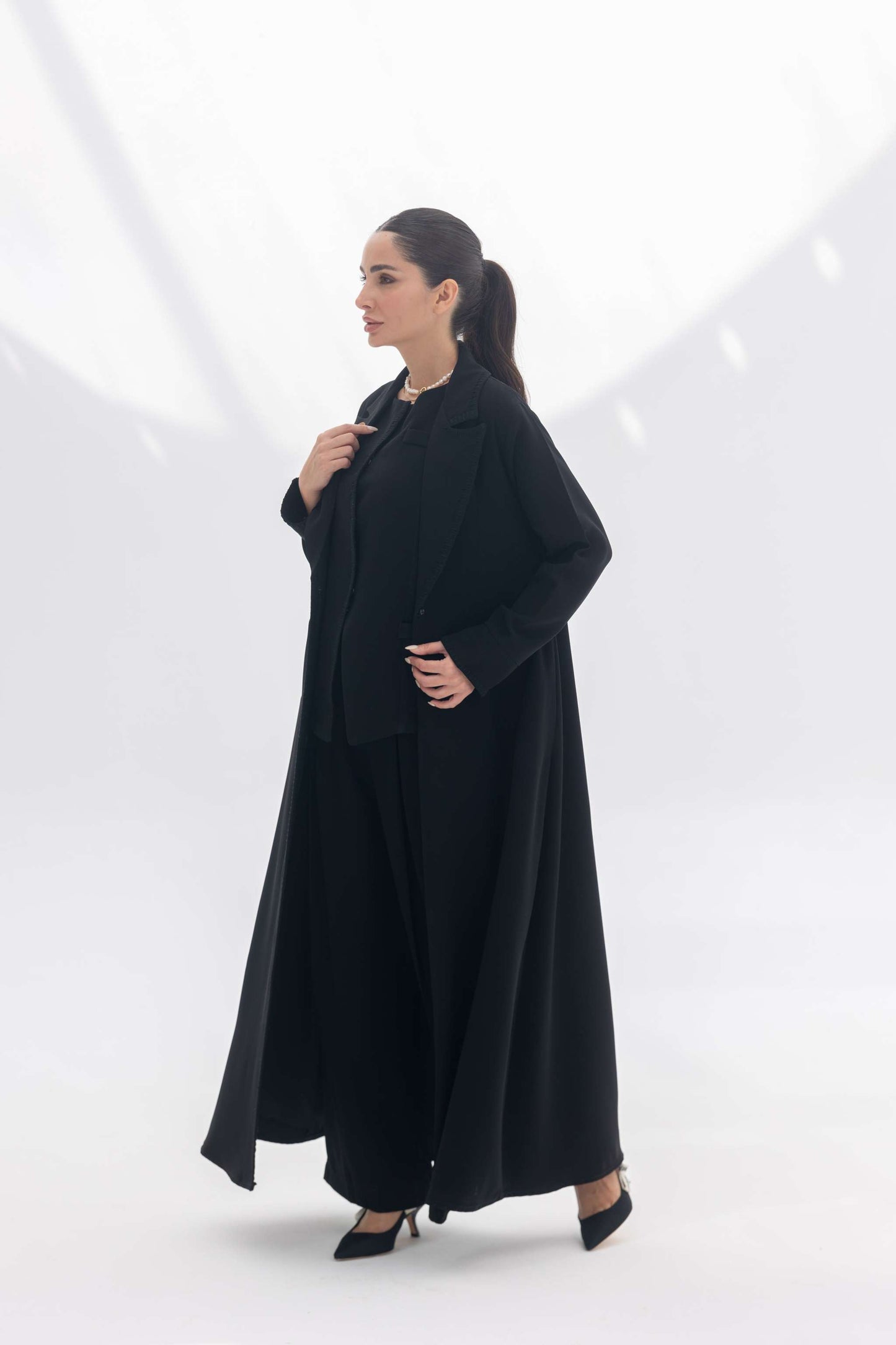 Woman wearing a black crepe blazer abaya with intricate embroidery and matching pants in a tailored silhouette for formal occasions