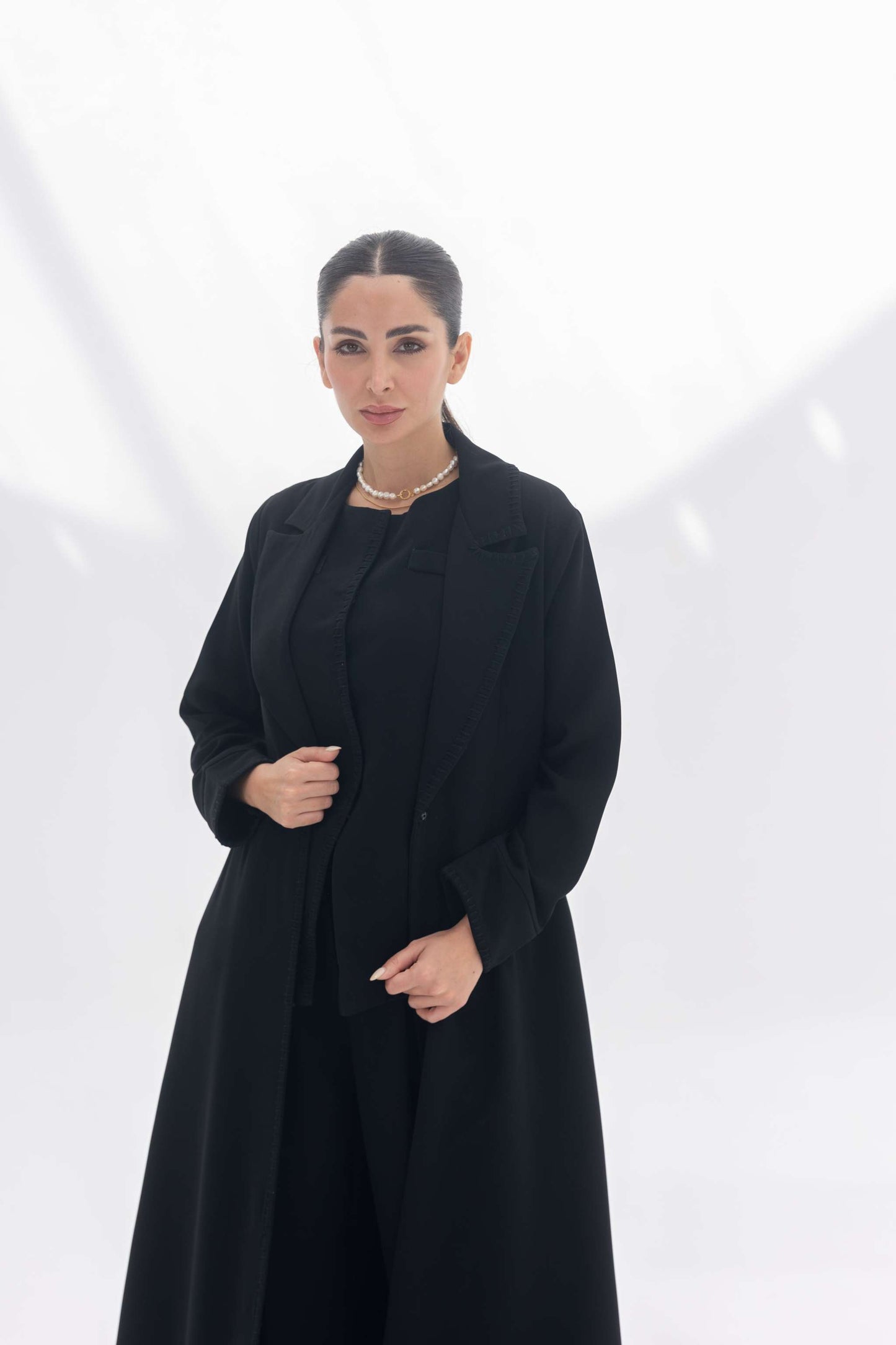 Woman wearing a sophisticated black crepe blazer abaya with tailored silhouette and intricate embroidery.