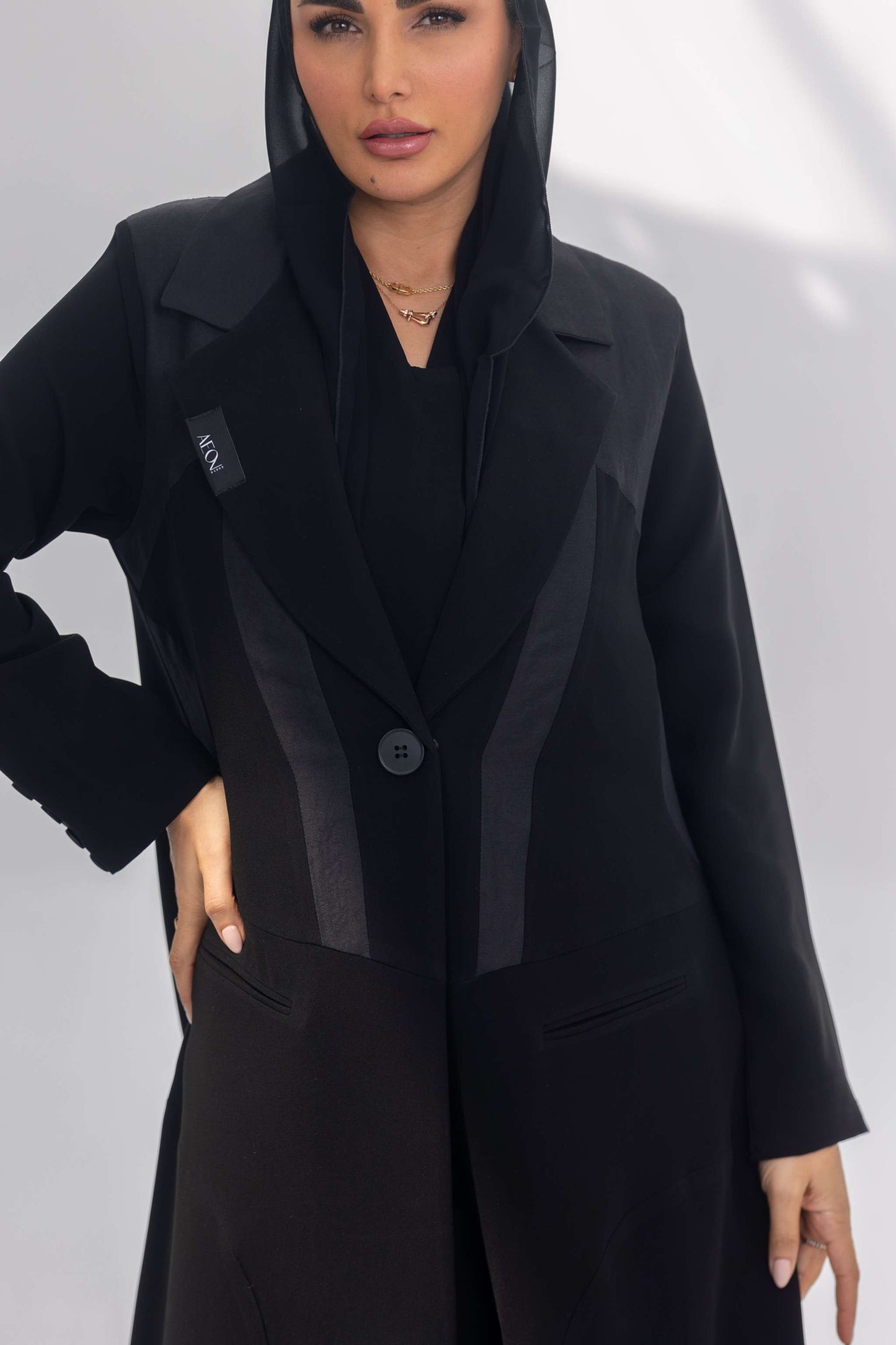 Black crepe abaya with dark grey fabric accents and soft silk lining, front-open design with sleek silhouette.