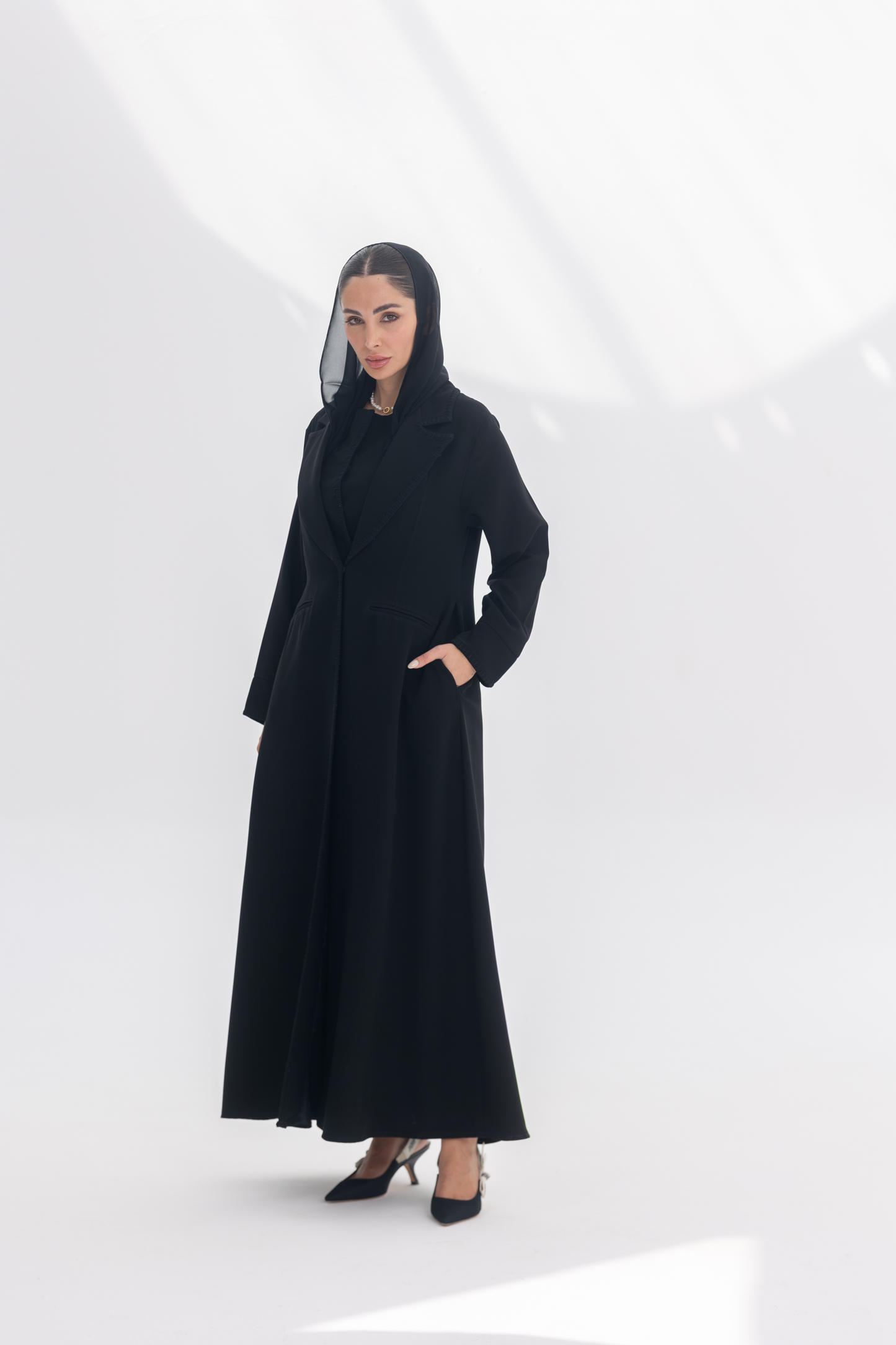 Woman wearing black crepe blazer abaya with tailored silhouette and subtle black embroidery, styled with matching inner and pants.