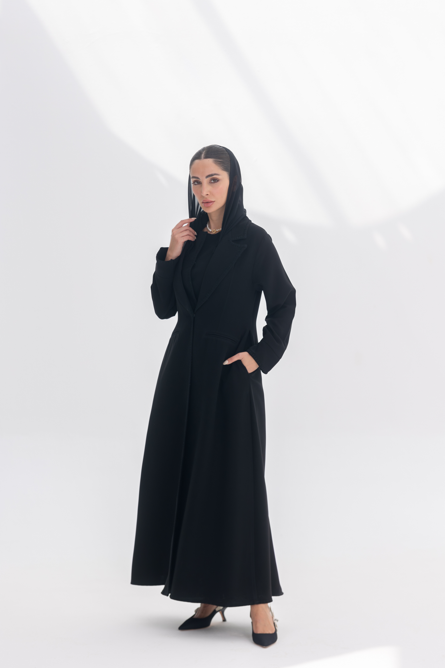 Woman wearing elegant black crepe blazer abaya with tailored silhouette and intricate embroidery, styled with matching black inner and pants.