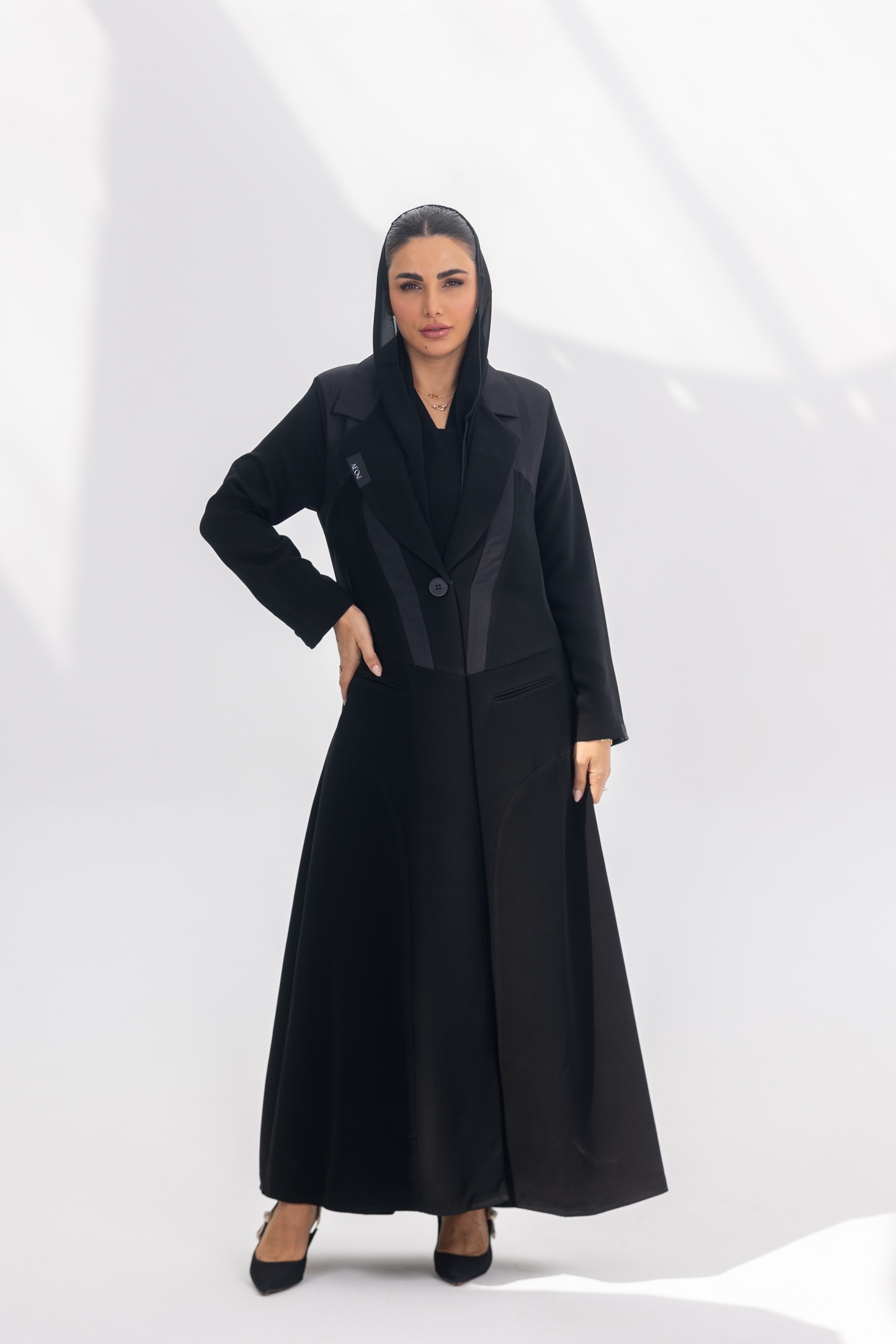 Woman wearing elegant black crepe Jetline abaya with dark grey accents and silk lining, front-open style.