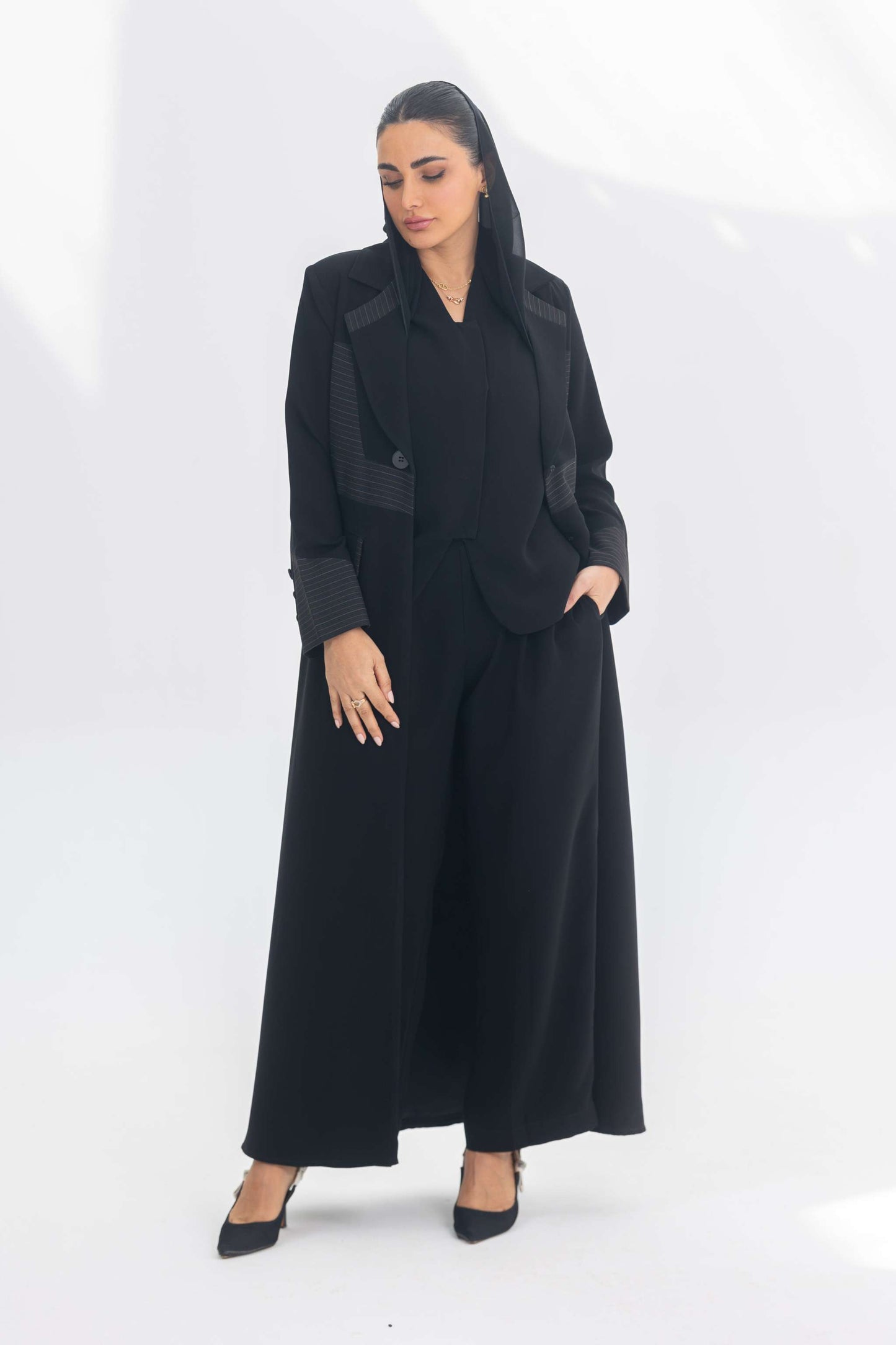 Woman wearing elegant black crepe blazer abaya with contrasting fabric details and long silhouette.