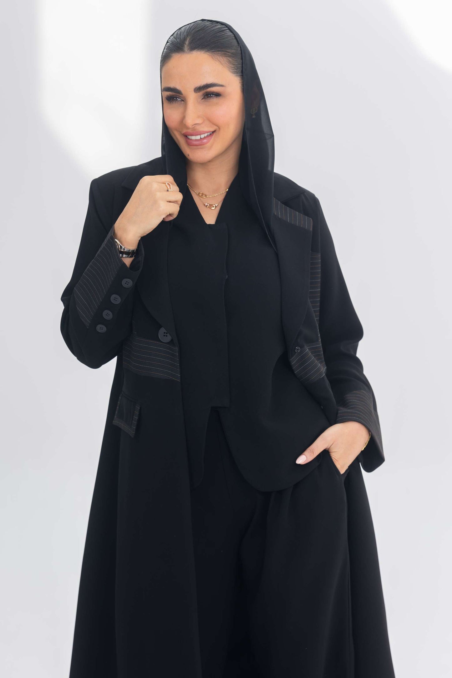 Woman wearing a black crepe blazer abaya with contrasting fabric details, combining modern elegance and regal sophistication.
