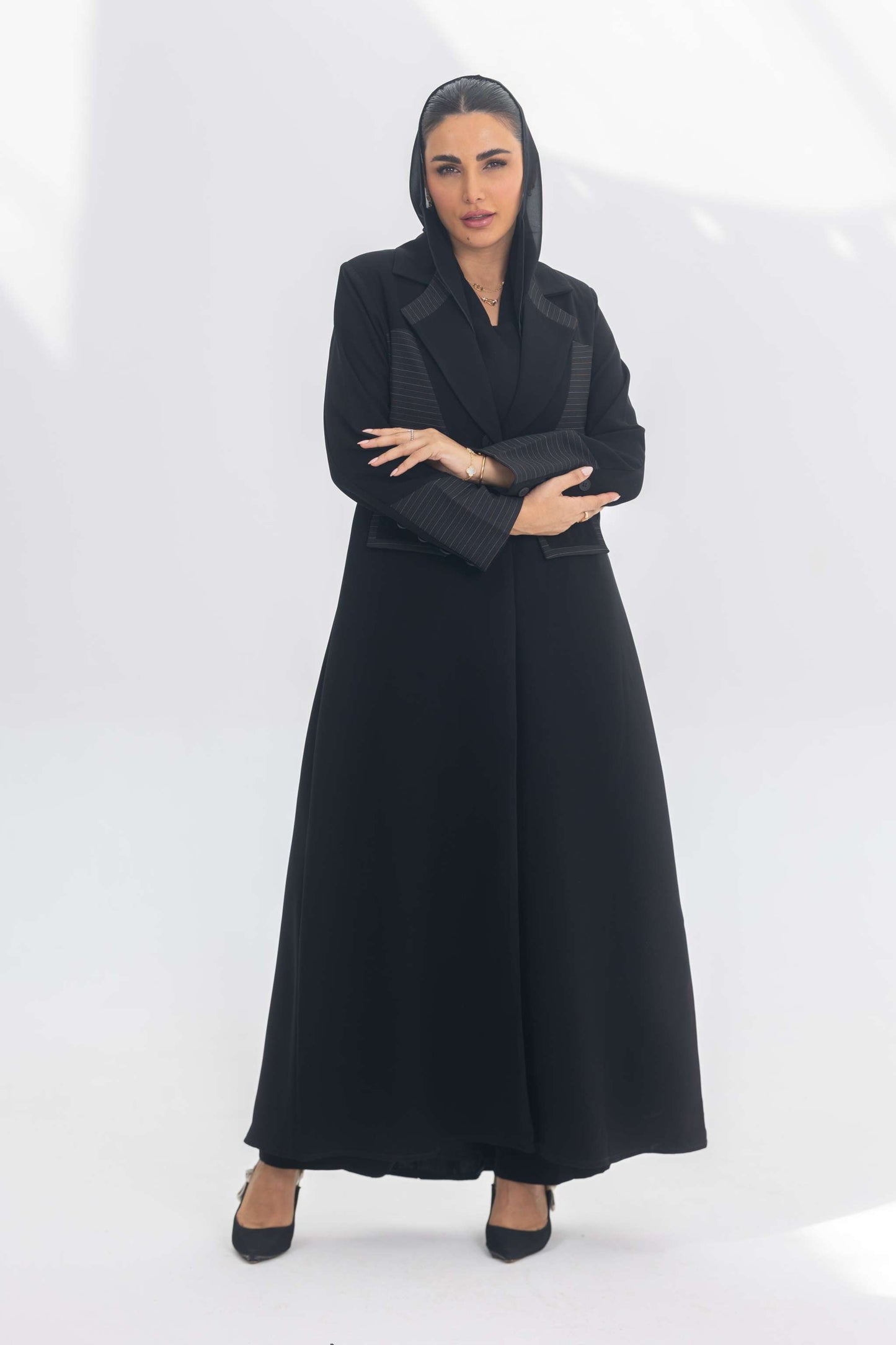 Woman wearing black crepe blazer abaya with contrasting textures, standing confidently against white background.