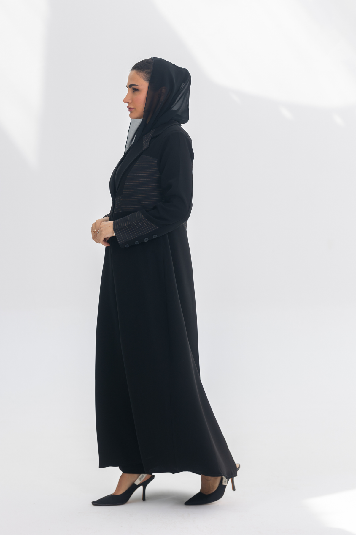 Elegant black crepe blazer abaya with contrasting fabric detail, worn with a black headscarf and heels, styled for modern sophistication.