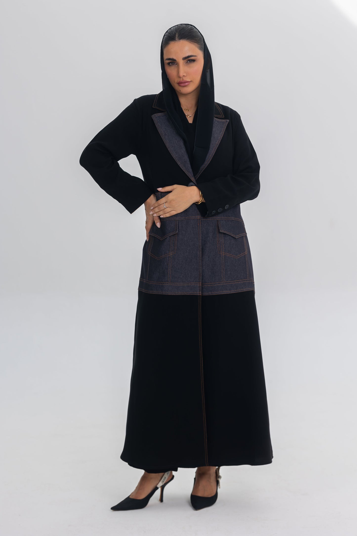 Woman wearing Blue Stitch abaya combining black crepe with denim fabric and modern design.