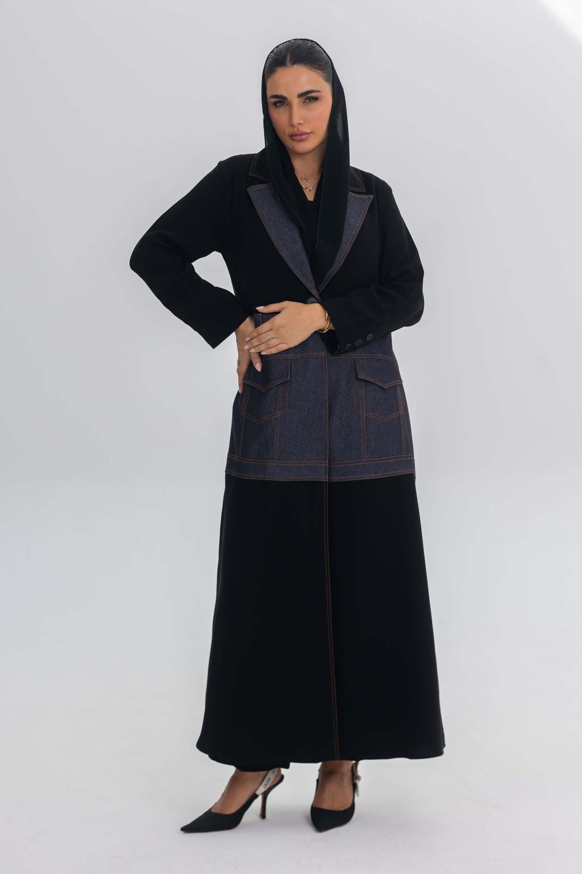 Woman wearing Blue Stitch abaya combining black crepe with denim fabric and modern design.