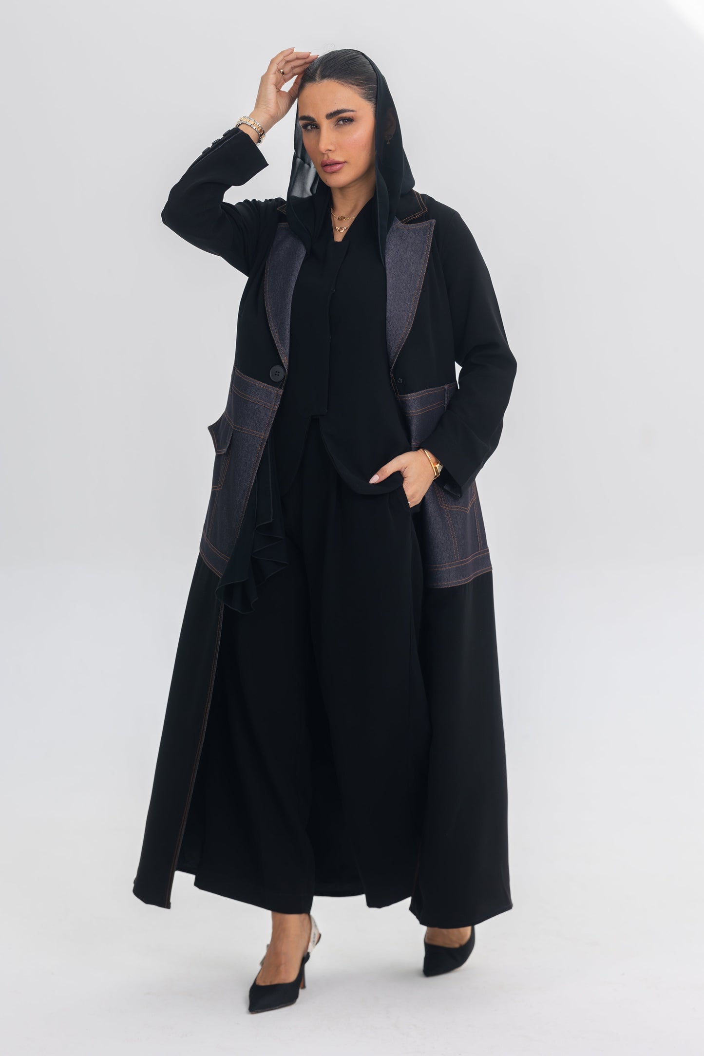 Woman wearing a black crepe abaya with denim fabric and blue stitch details, showcasing contemporary elegance.