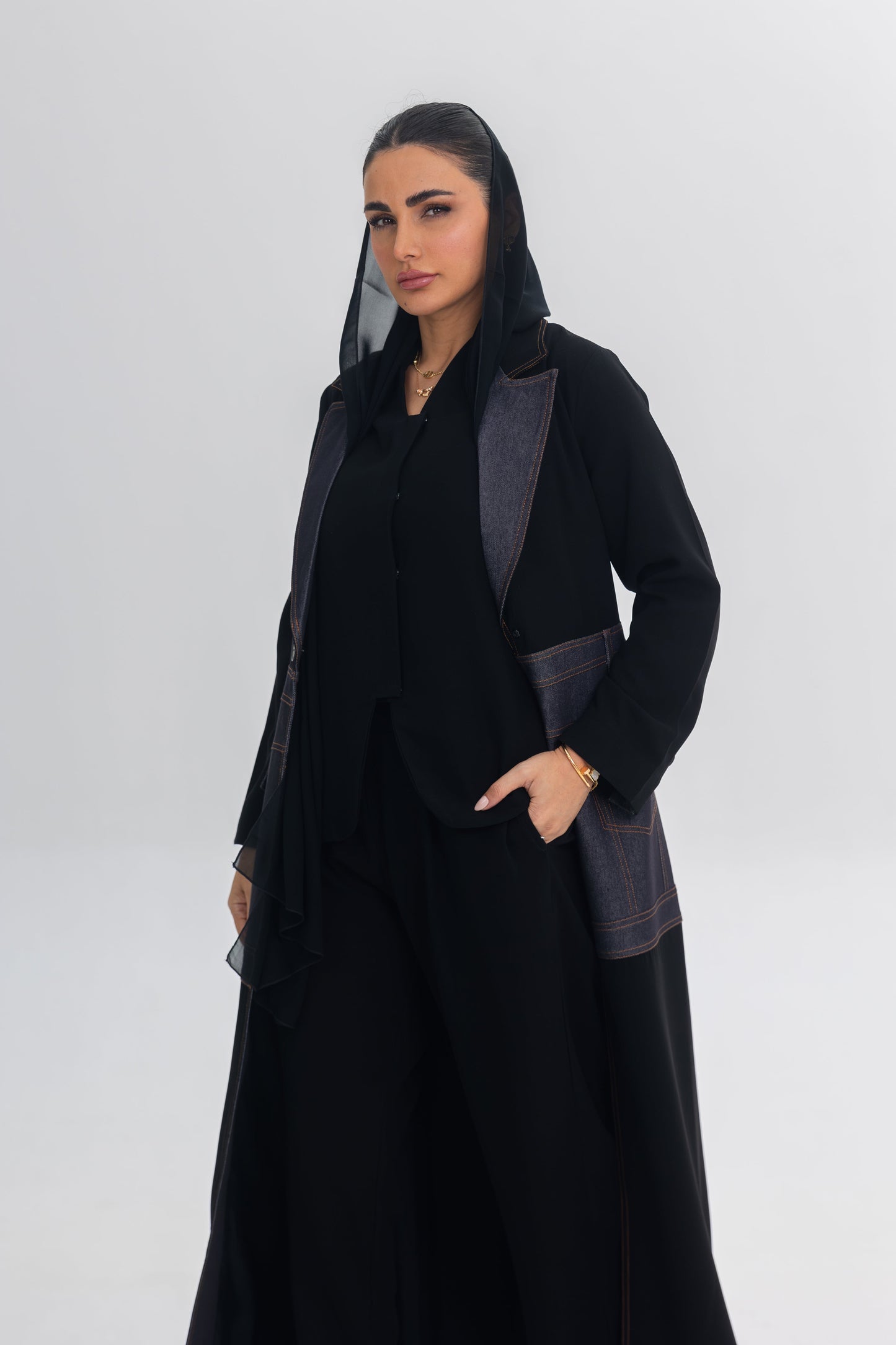 Woman wearing sleek black crepe abaya with edgy denim blue stitch detailing and modern design