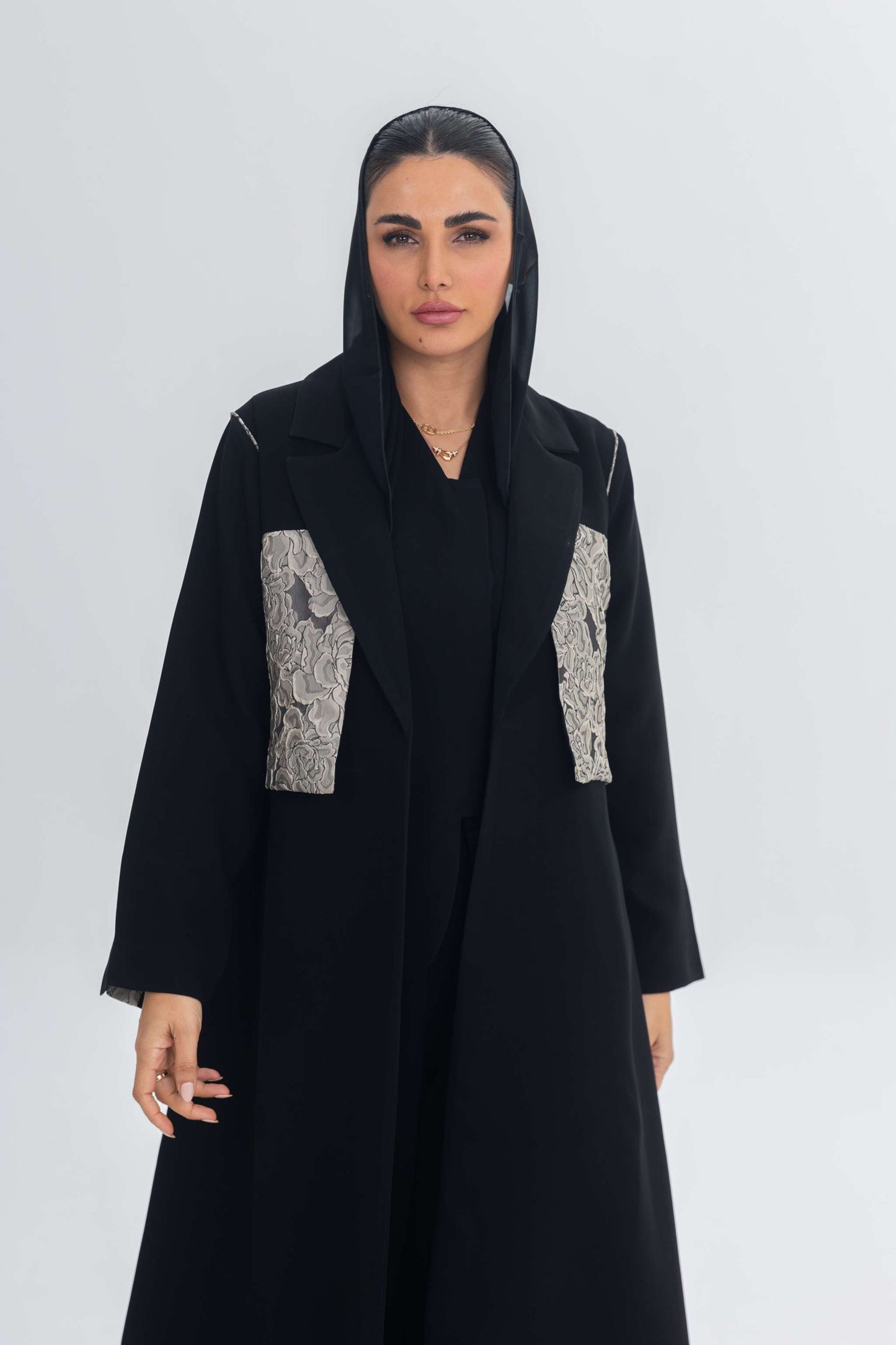 Black crepe abaya with jacquard panel detail on front worn by woman with black headscarf