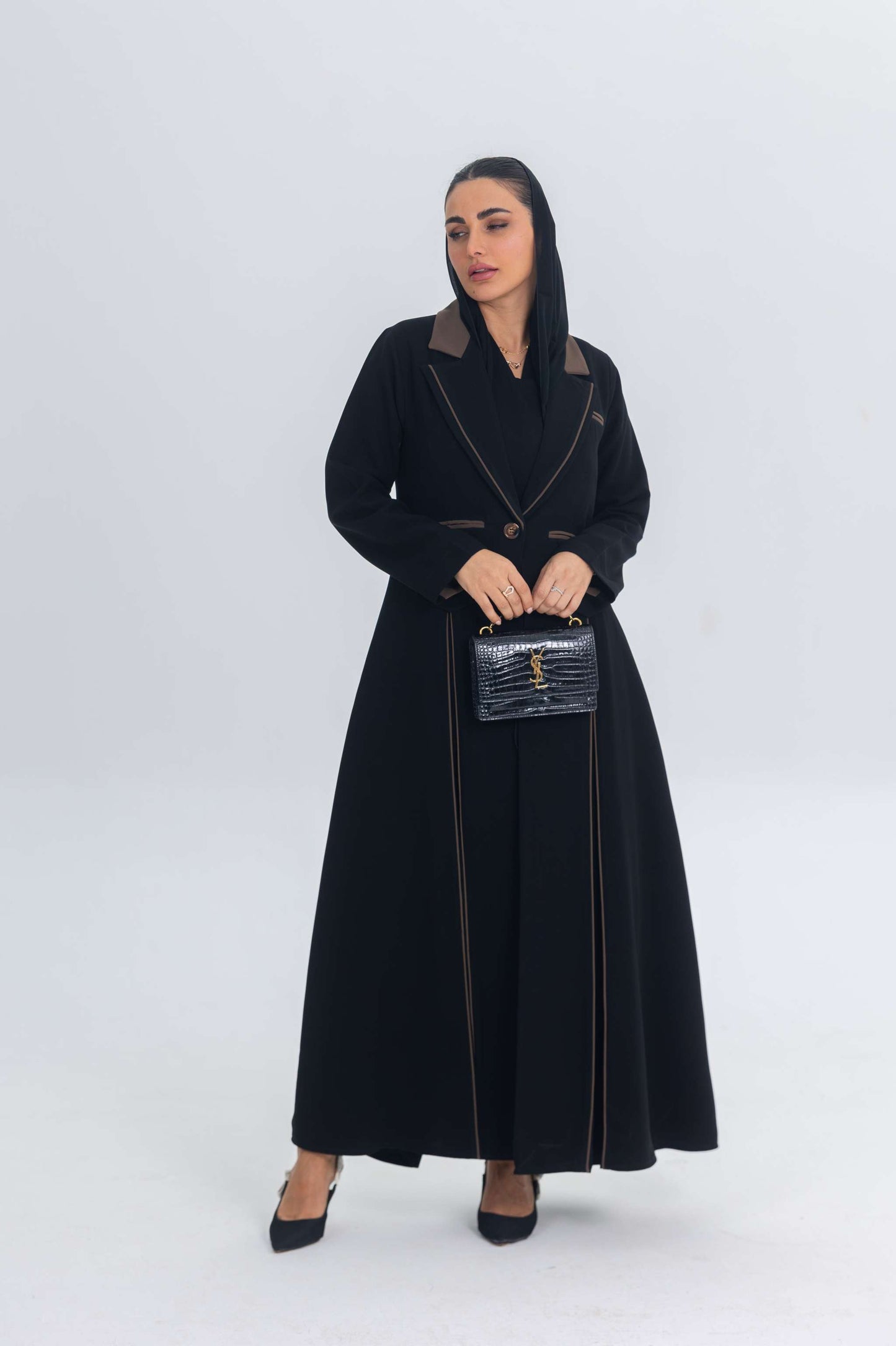 Black crepe blazer abaya with brown trims and detailing, sleek silhouette, and elegant, modern minimalist style.