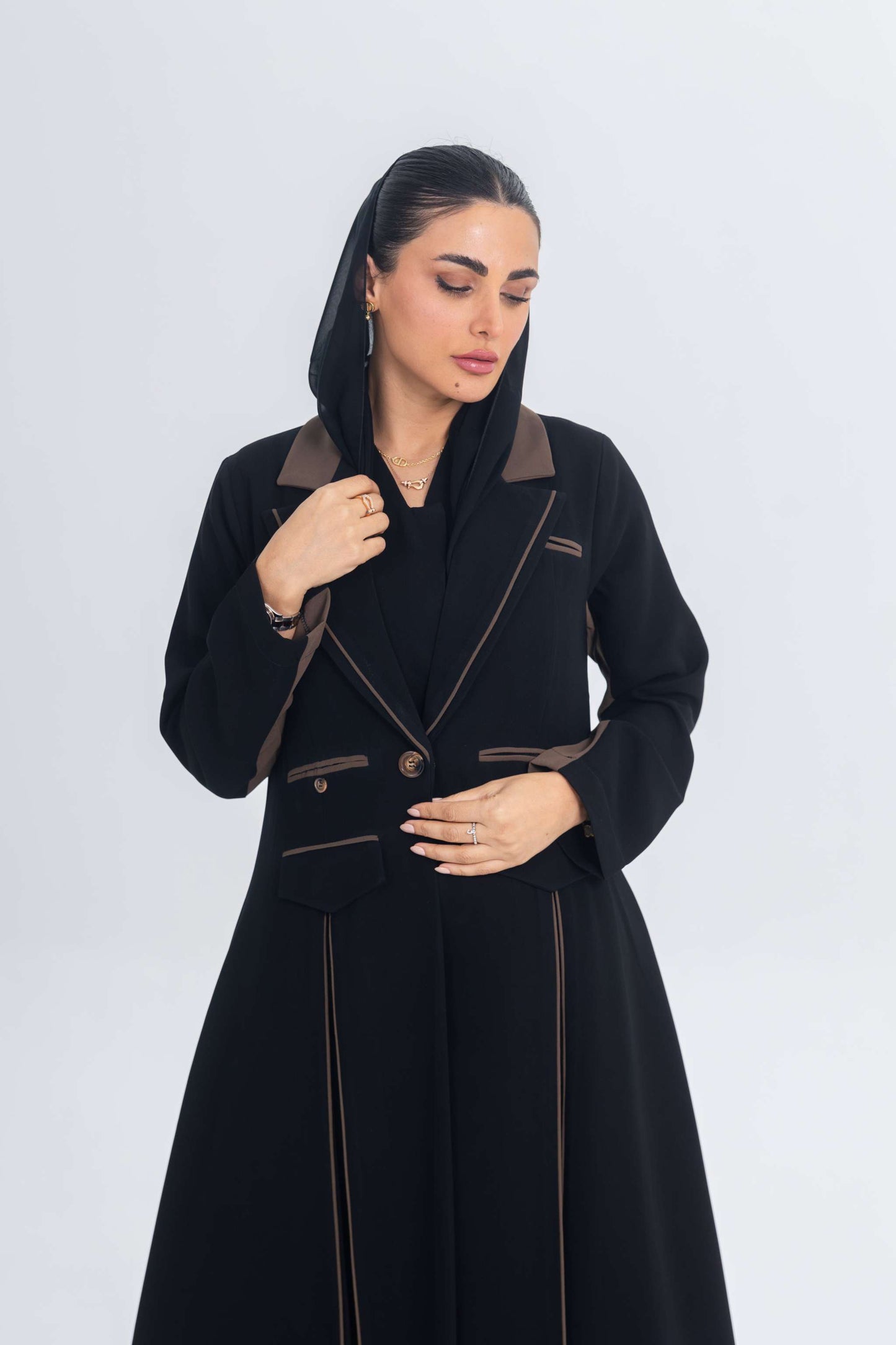 Woman wearing a black crepe blazer abaya with brown trim and detailing, showcasing elegant and sleek design.
