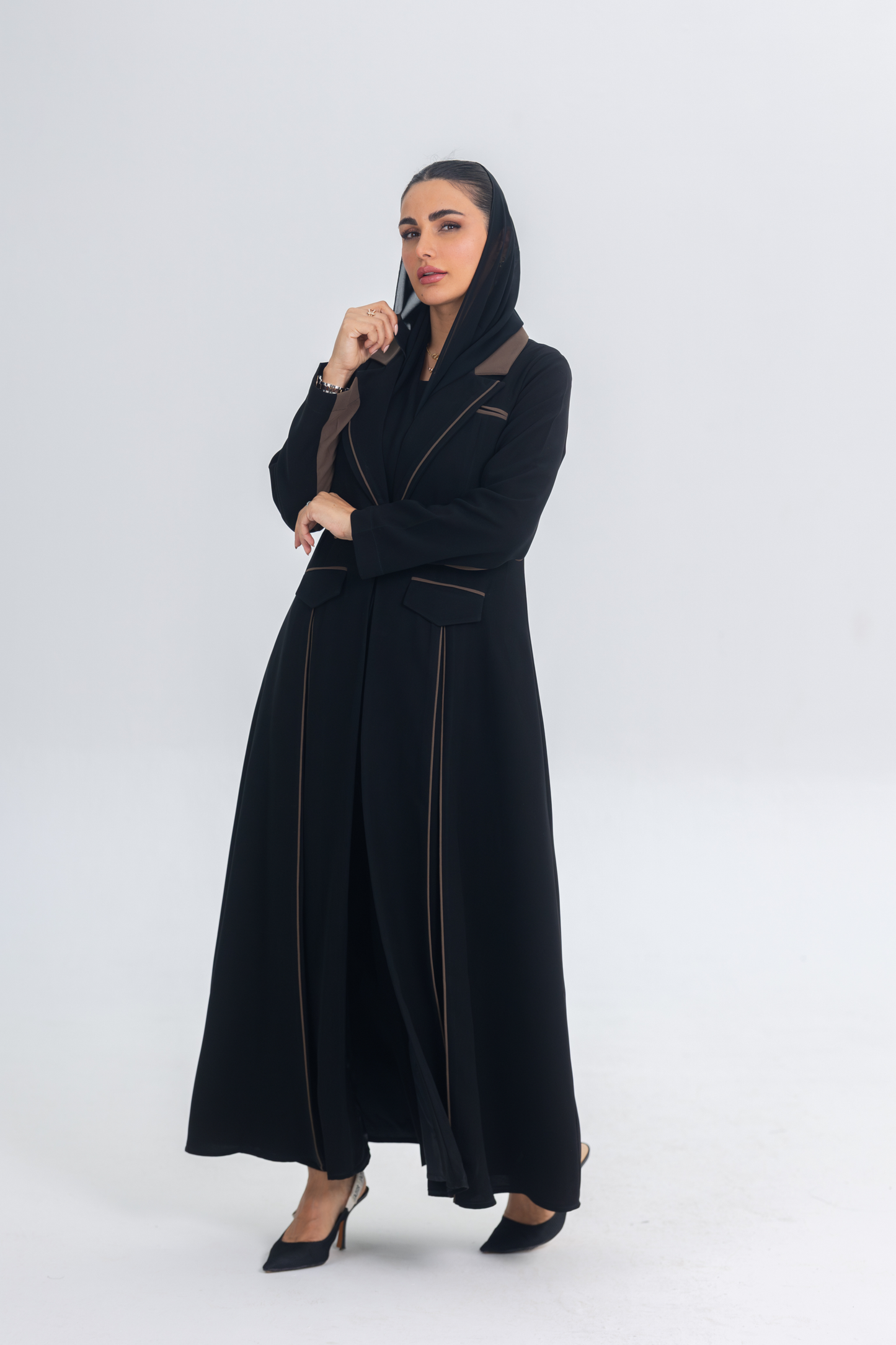 Woman wearing black crepe blazer abaya with chestnut brown trim and detailing, elegant and modern style.