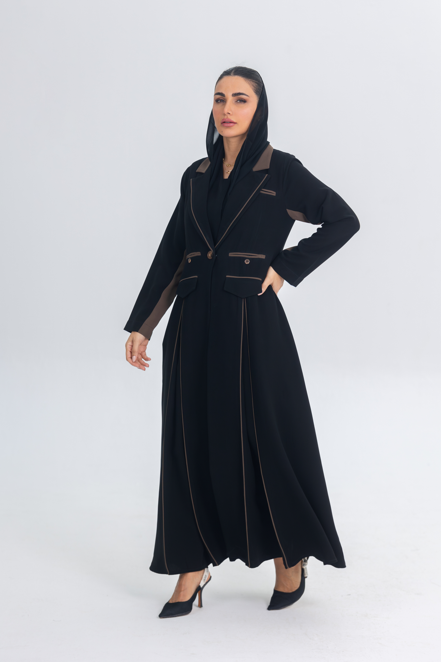 Black crepe blazer abaya with brown accents and sleek flowing silhouette worn by woman in heels