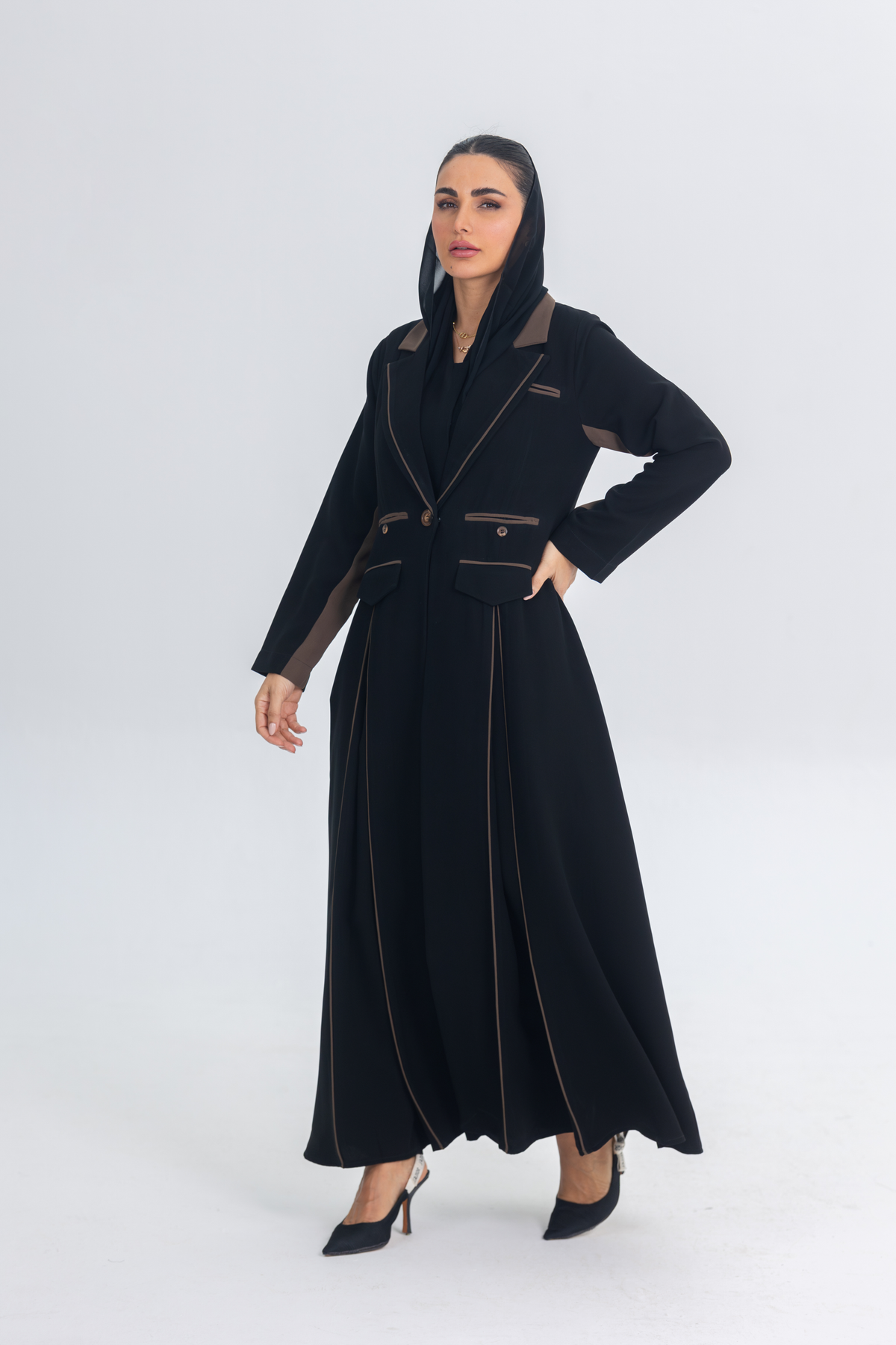 Black crepe blazer abaya with brown accents and sleek flowing silhouette worn by woman in heels