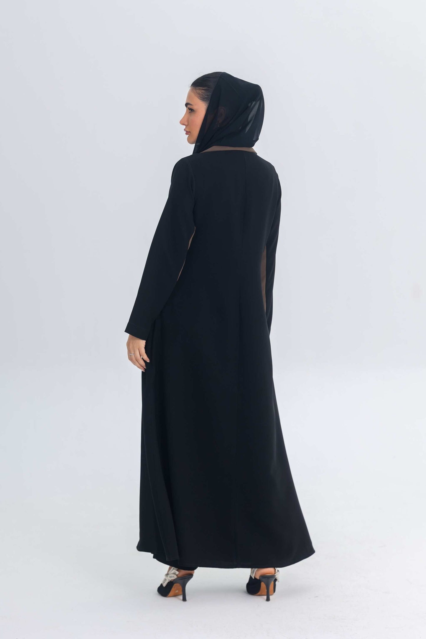 Woman wearing black crepe blazer abaya with brown trim detailing viewed from the back