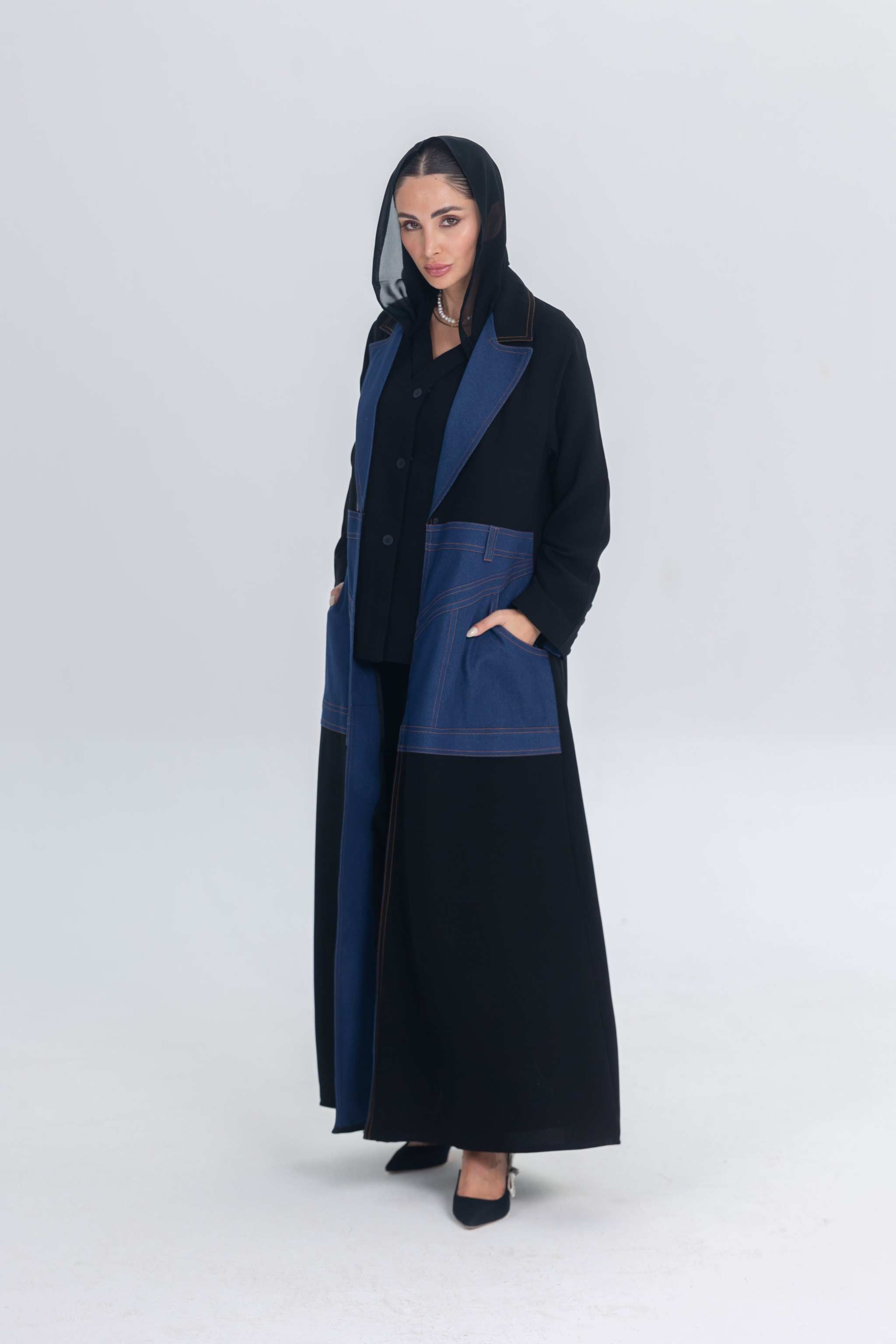 Woman wearing a black crepe abaya with denim panels and collar detailing in a formal style
